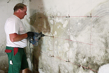 Handwerker bohrt Kanäle, in die später die Veinal Horizontalsperre injiziert wird