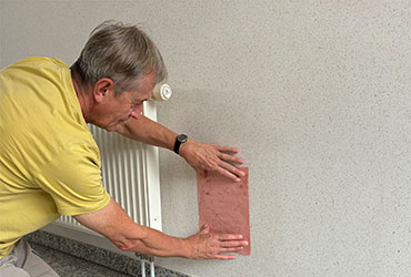 Veinal_Kettenreaktion_Vorschau-1 Man hält ein Löschblatt an eine feuchte Wand.